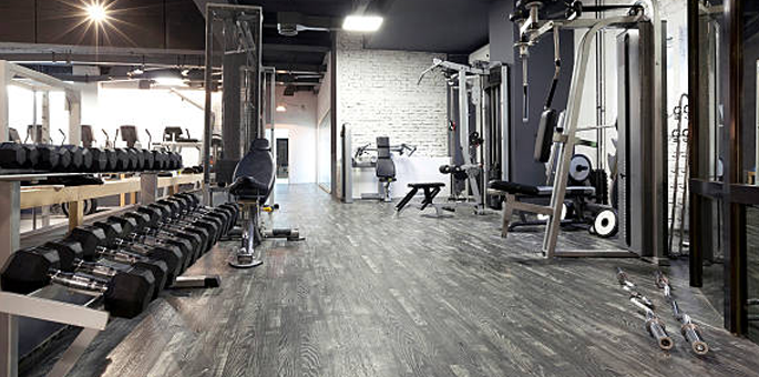 Modern gym interior with rows of dumbbells and weight machines on a wooden floor