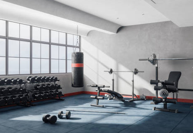 Bright gym room with a rack of dumbbells and a weight bench, large industrial windows