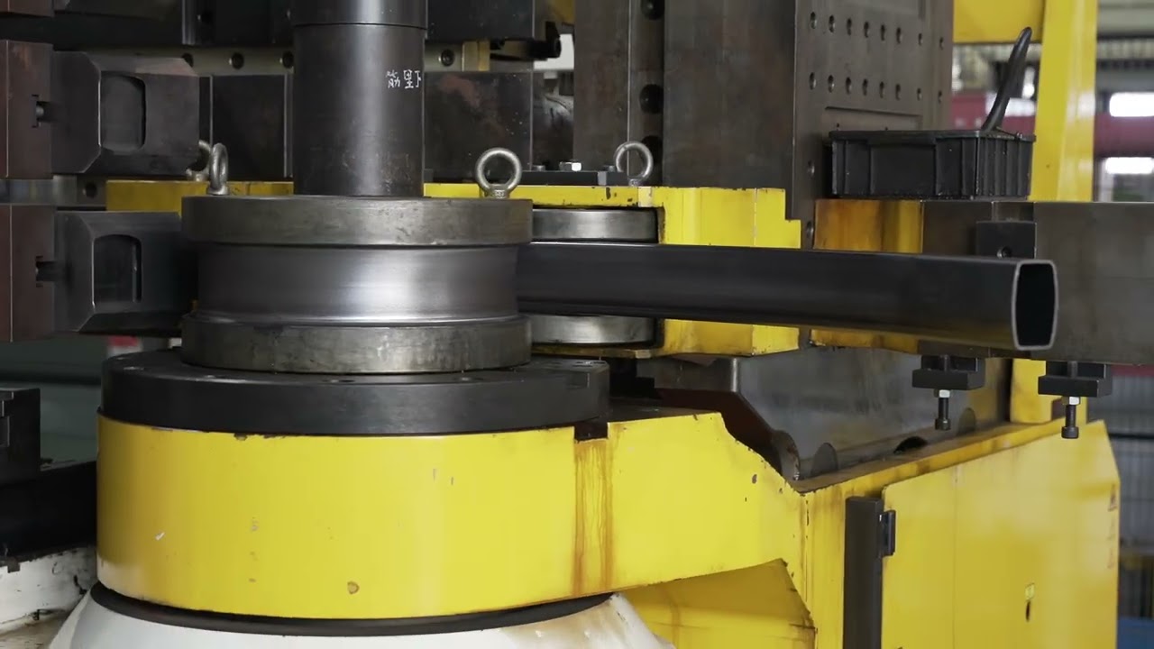 A worker in a blue uniform operating a large industrial machine with a digital screen interface