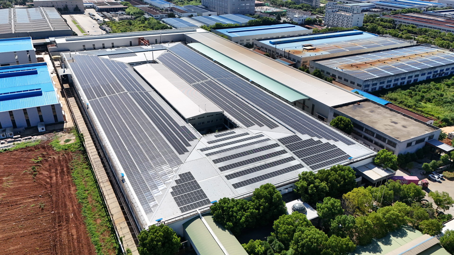 Aerial view of a large manufacturing facility with solar panels on the roof
