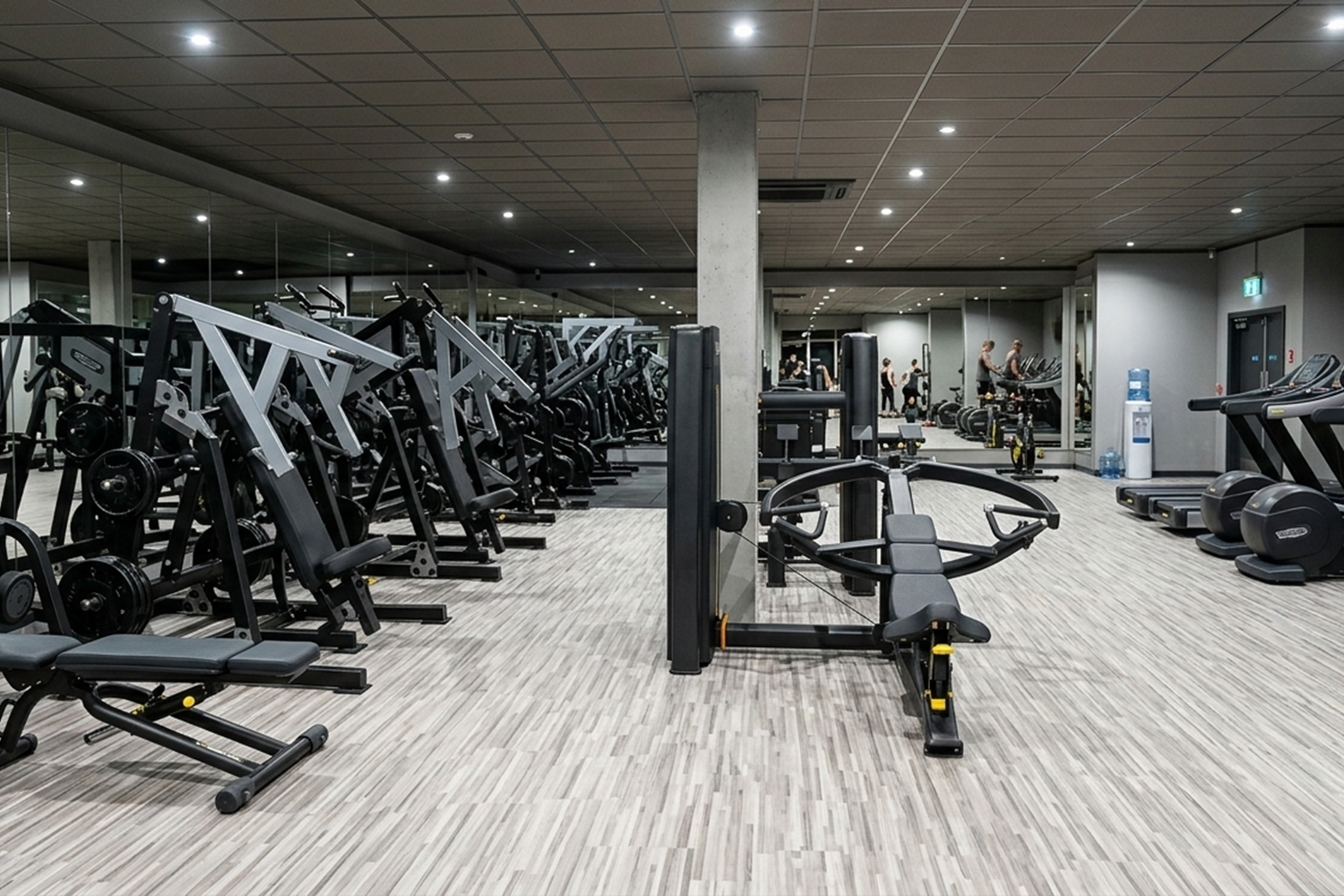 Large commercial gym floor filled with rows of black strength machines