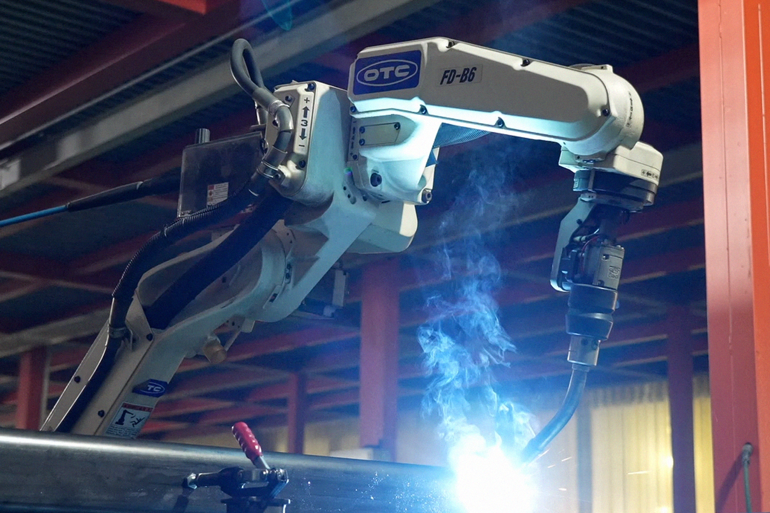 Close up of a blue robotic welding arm in operation, emitting bright sparks