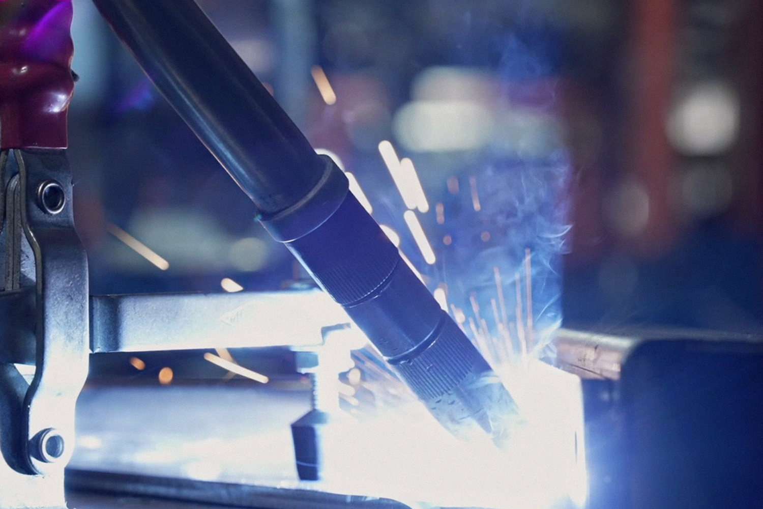 Close up of a robotic welding arm creating sparks on metal in a factory setting