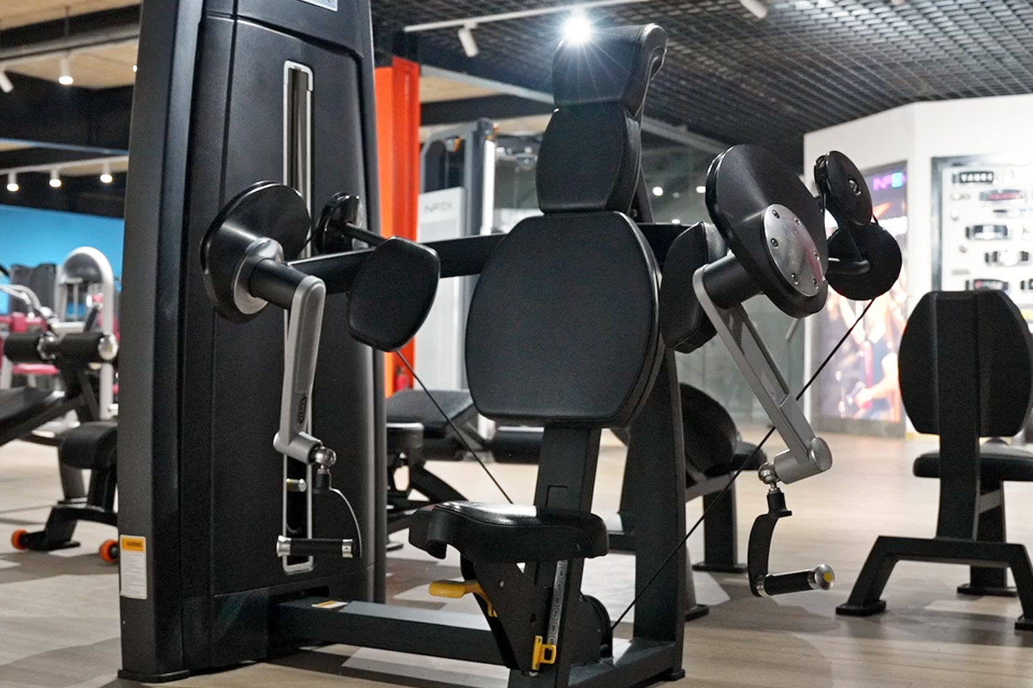 Close up view of commercial gym equipment showing weight stack, pulleys, and seat padding