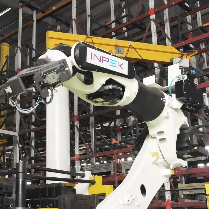 Robotic arm welding a white metal frame in a factory